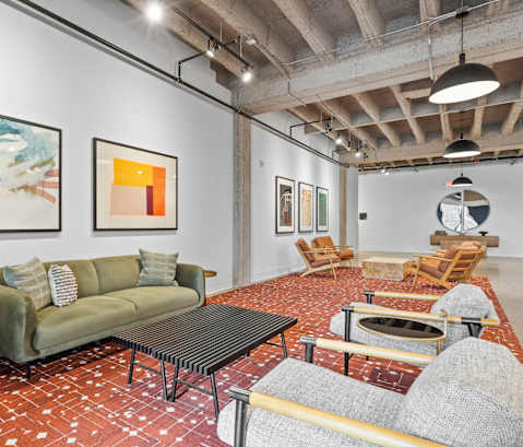 A living room with a green couch and a painting on the wall.