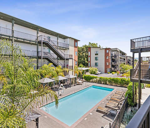 A pool surrounded by a balcony and trees.