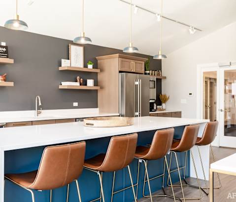 A modern kitchen with a white countertop and blue accent chairs.