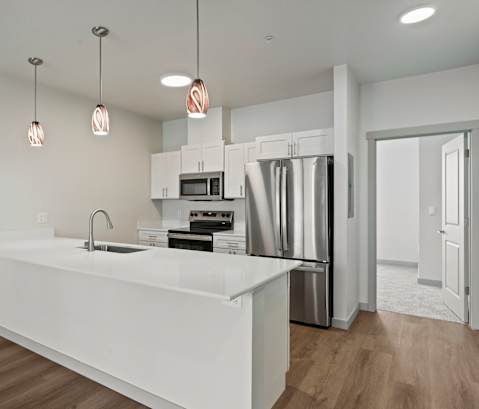 A modern kitchen with a white countertop and stainless steel appliances.