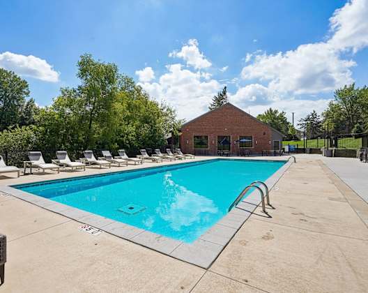 A large swimming pool surrounded by lounge chairs and trees.
