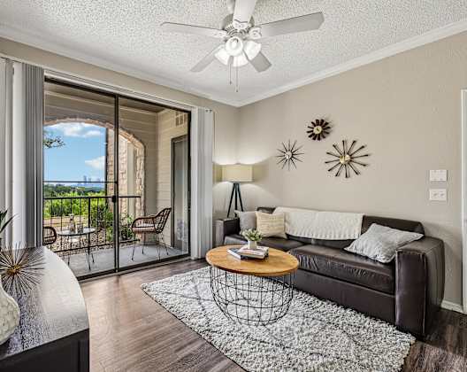 A living room with a brown couch, a coffee table, and a ceiling fan.
