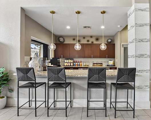A bar area with four black chairs and a counter with a person behind it.