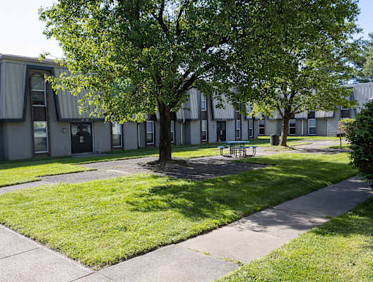 a courtyard with trees and a picnic table in front of a building