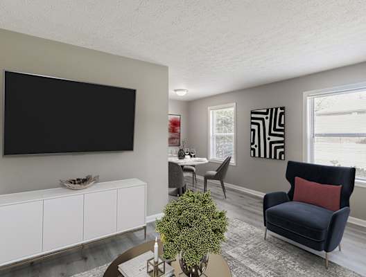 a living room with a tv on the wall and a table and chairs in the background