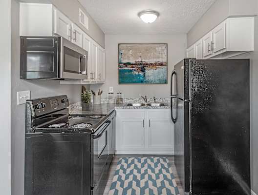 a kitchen with white cabinets and black appliances