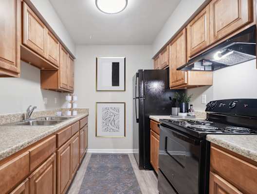 A kitchen with black appliances and wooden cabinets.