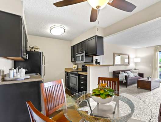 a kitchen and living room with a table and chairs and a ceiling fan