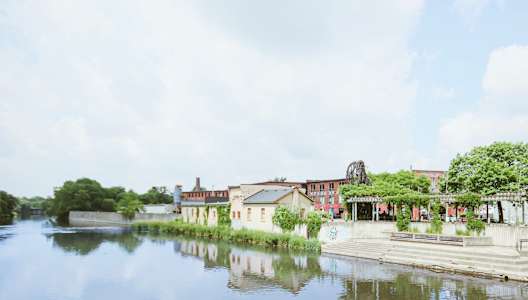 A serene riverside scene with a building and a dock.