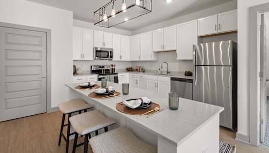 A modern kitchen with a white island and stainless steel appliances.