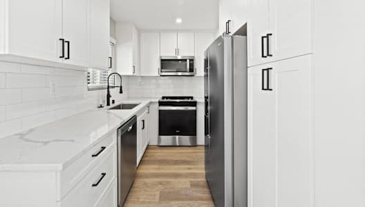 a white kitchen with stainless steel appliances and white cabinets