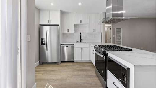 a renovated kitchen with white cabinets and stainless steel appliances