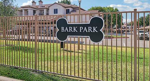 A sign that says Bark Park is on a fence.
