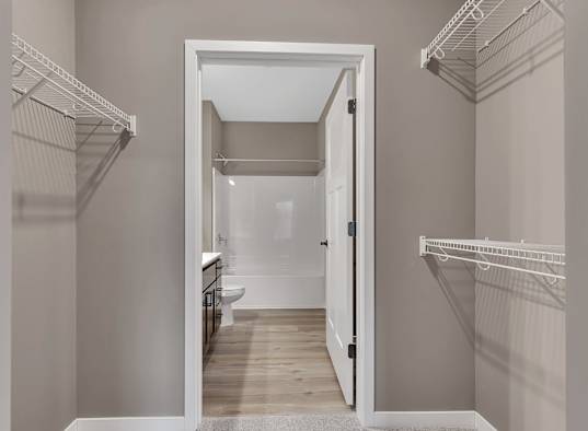 A white doorway leads to a bathroom with a toilet and sink.