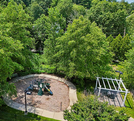 A playground with a green slide and a white swing set.