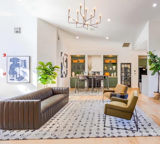 A large, modern living room with a grey sofa, a yellow armchair, and a patterned rug.