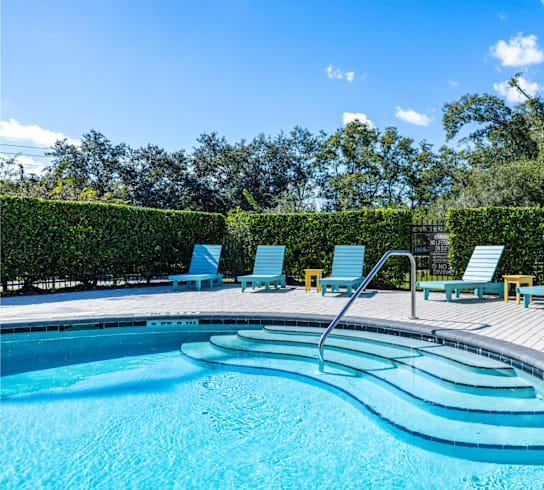 A swimming pool with blue water and lounge chairs.
