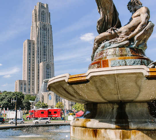 a fountain with a statue in front of a tall building at University Commons in Pittsburgh, PA