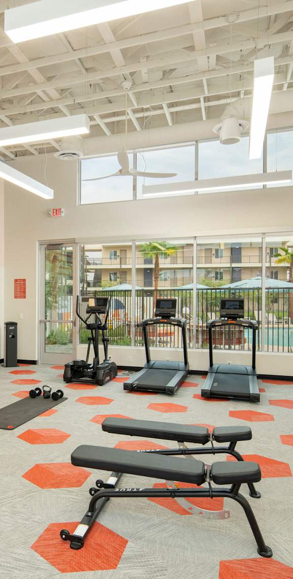 A gym with orange and white walls and a variety of equipment.