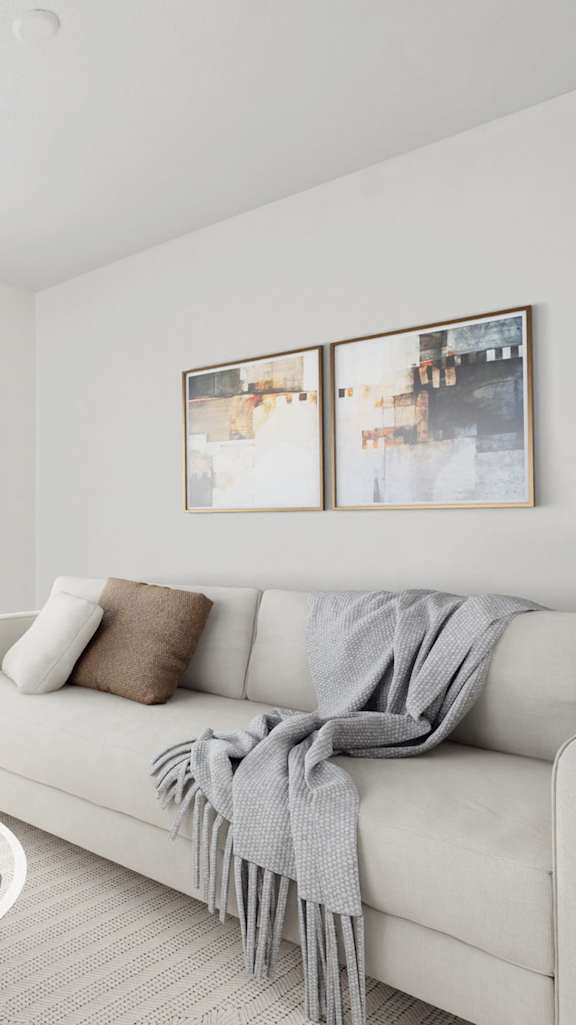 A modern living room with a grey sofa, a coffee table, and a painting on the wall.