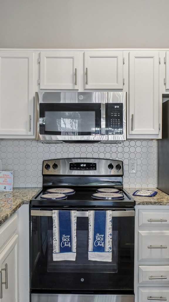A kitchen with a black stove top oven and a black microwave above it.
