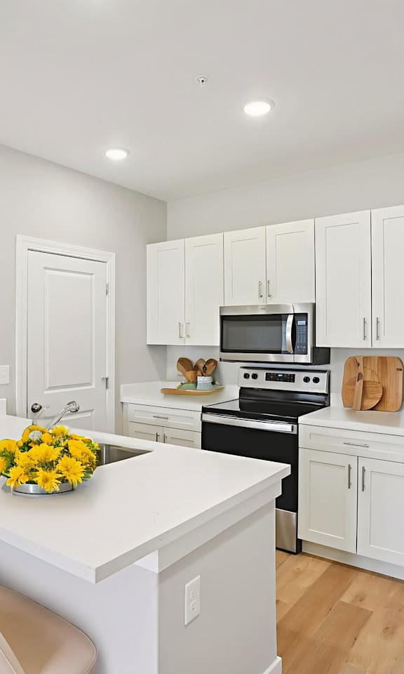 A kitchen with white cabinets and a stainless steel refrigerator.