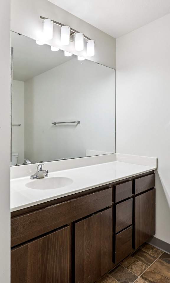 A bathroom with a white sink and brown cabinets.