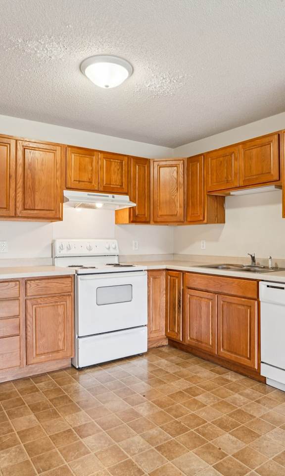 A kitchen with white appliances and wooden cabinets.
