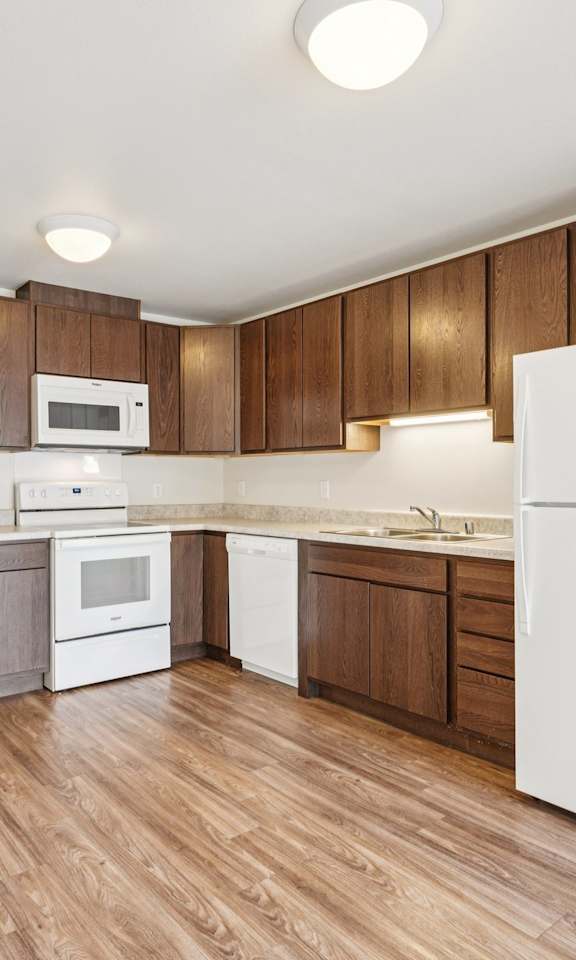 A kitchen with white appliances and wooden cabinets.