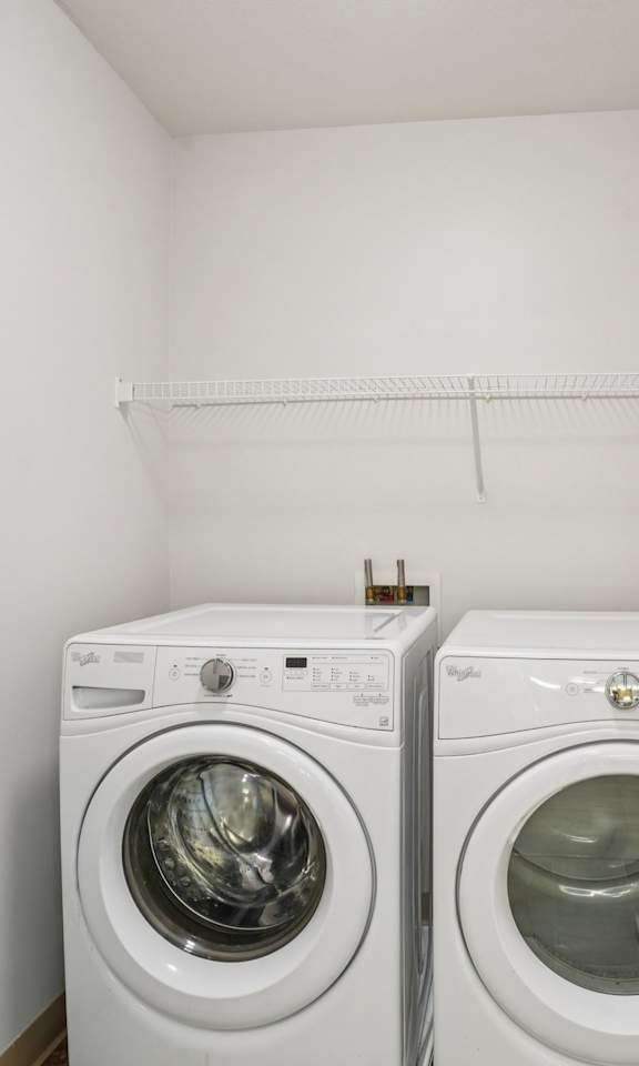 Two white front loading washing machines in a small laundry room.