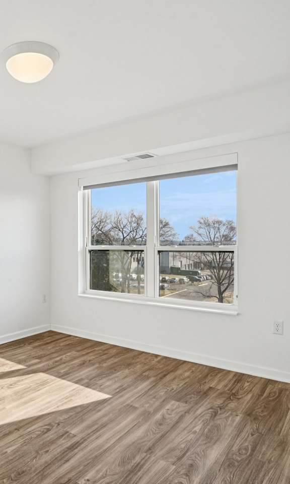 A room with a window and a wooden floor.