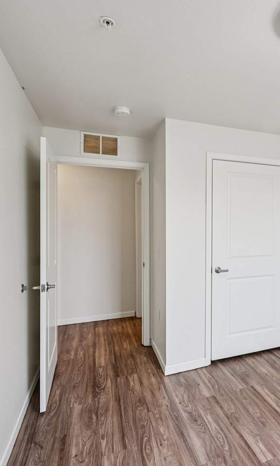 A room with a white door and a wooden floor.
