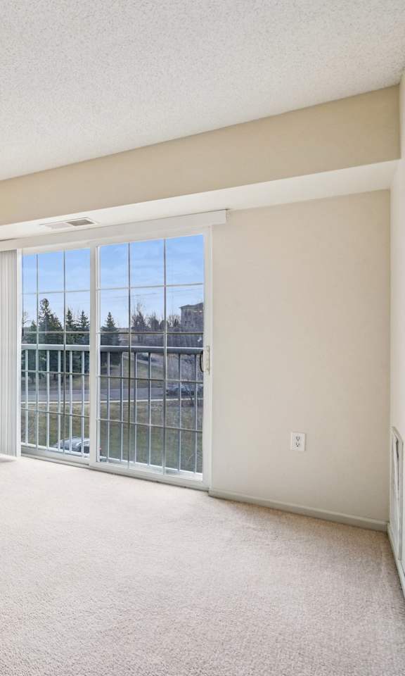Empty room with a sliding glass door leading to a balcony.