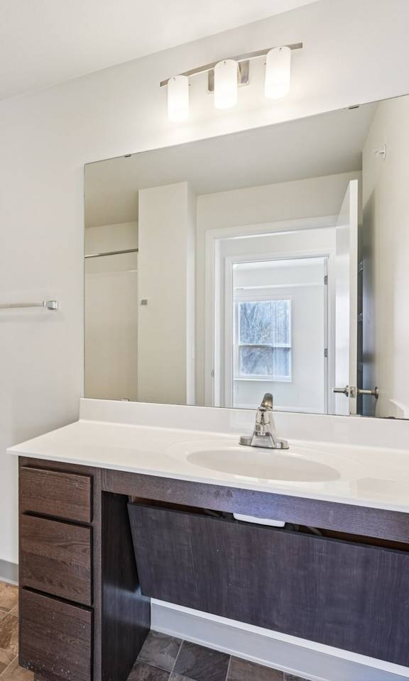 A bathroom with a toilet, sink, and mirror.
