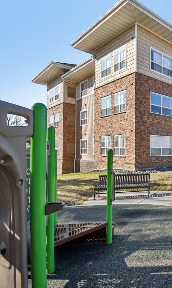 Apartment complex with a green pole and bench in front.