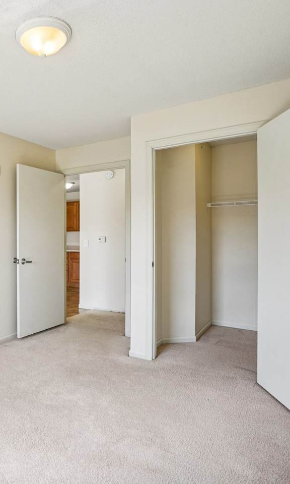 A white room with a carpeted floor and a door on the right.