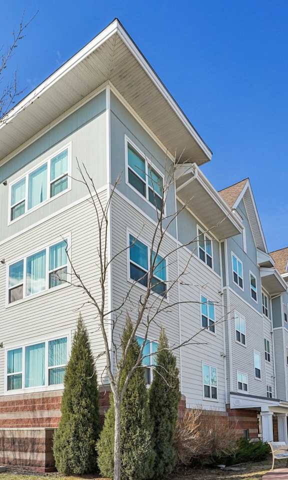 A large apartment building with a tree in front.