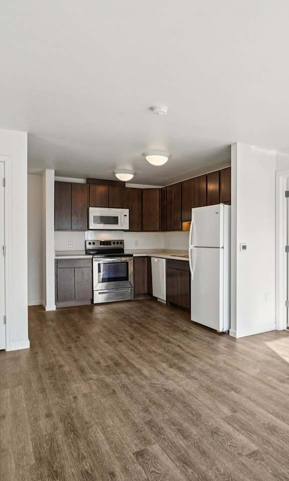 A kitchen with white appliances and wooden floors.