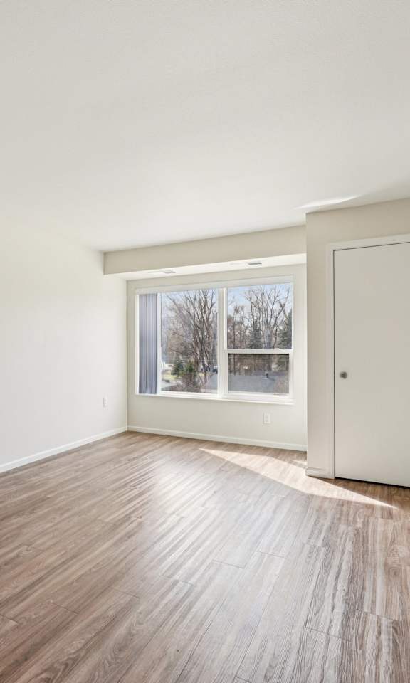 A room with a wooden floor and a door leading to a balcony.