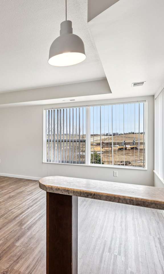 A room with wooden flooring and a window with blinds.