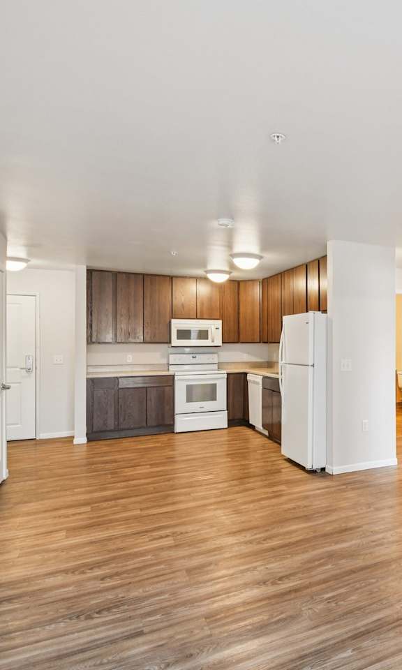 A kitchen with white appliances and wooden floors.