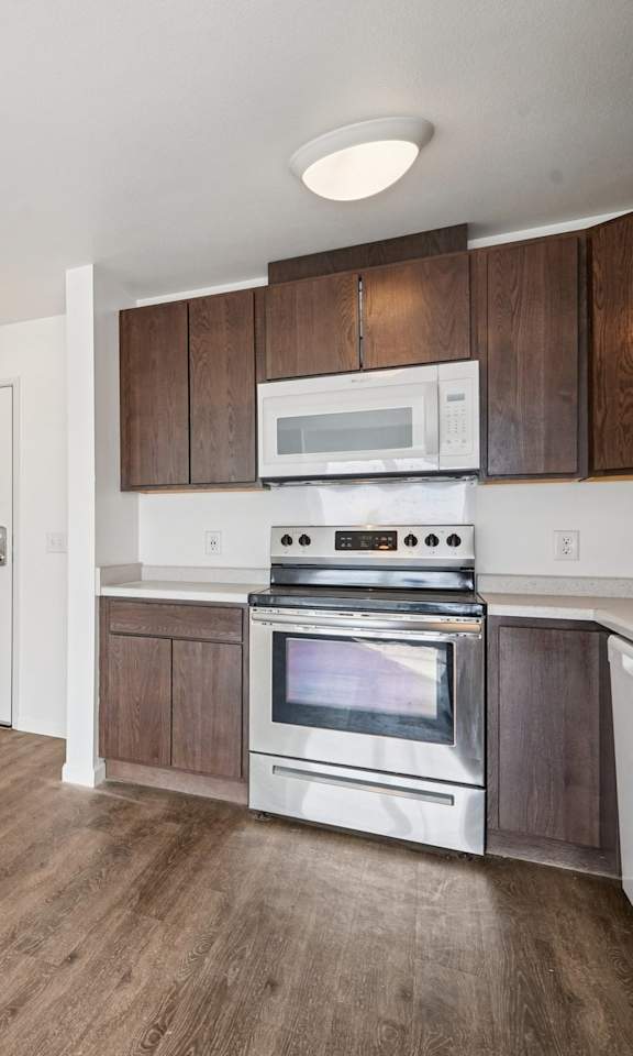 A kitchen with a white refrigerator, wooden cabinets, and a stainless steel stove.