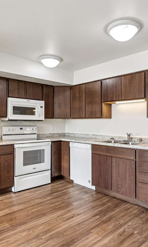 A kitchen with white appliances and wooden cabinets.