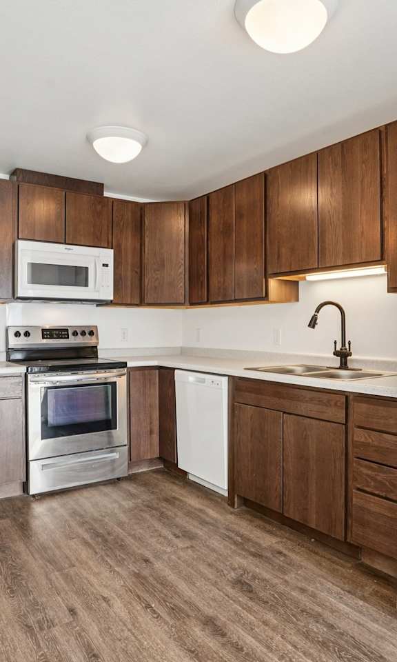 A white refrigerator is in the corner of a kitchen with wooden cabinets.