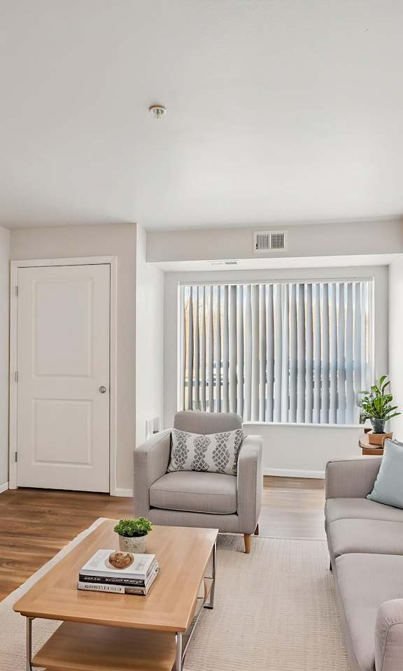 A living room with a grey couch, a wooden coffee table, and a flat screen TV mounted on the wall.