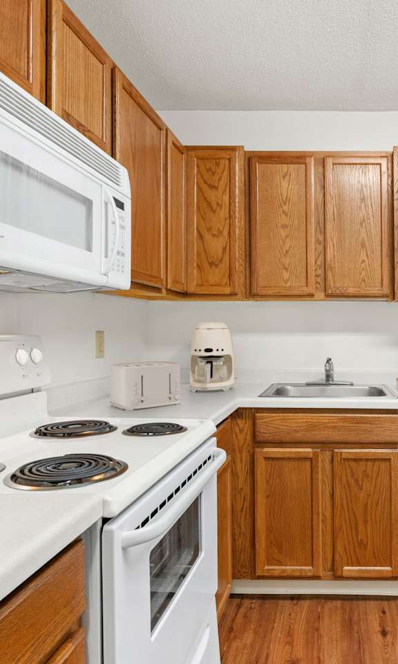 A kitchen with white appliances and wooden cabinets.