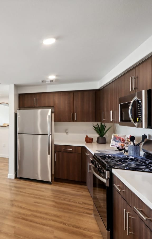 a large kitchen with wooden cabinets and stainless steel appliances at The Max on Jefferson Apartments, Murrieta, California