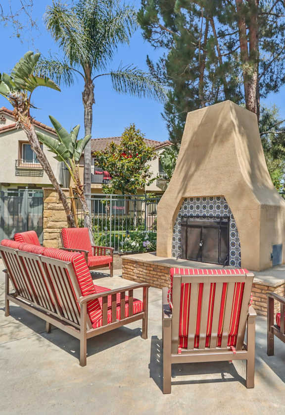 A patio with red chairs and a fireplace.