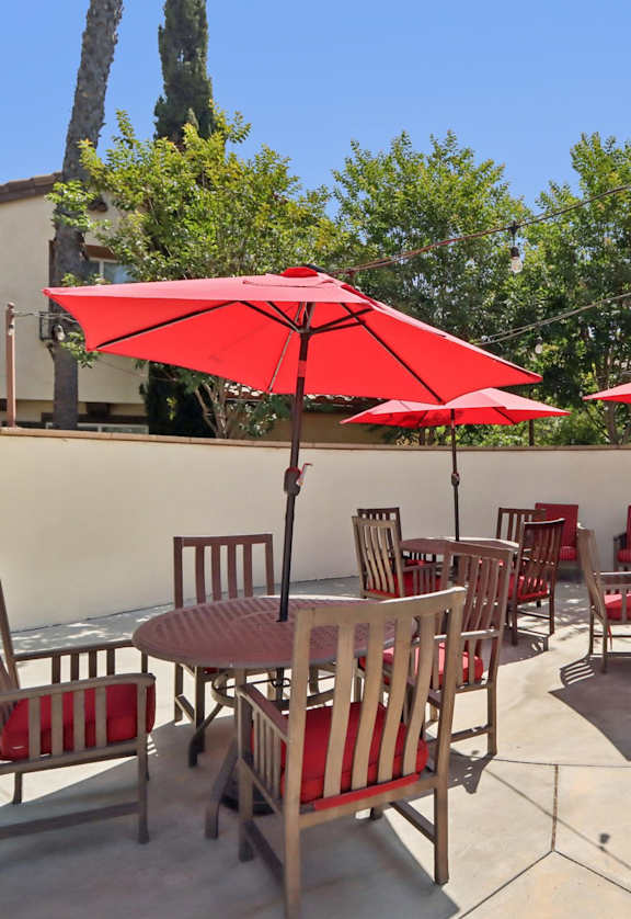 A patio with red umbrellas and chairs.
