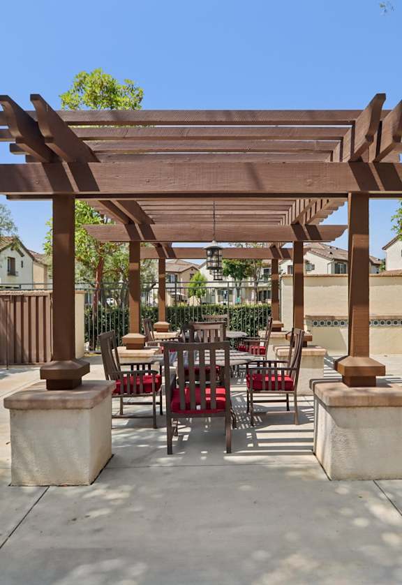A wooden pergola with red chairs